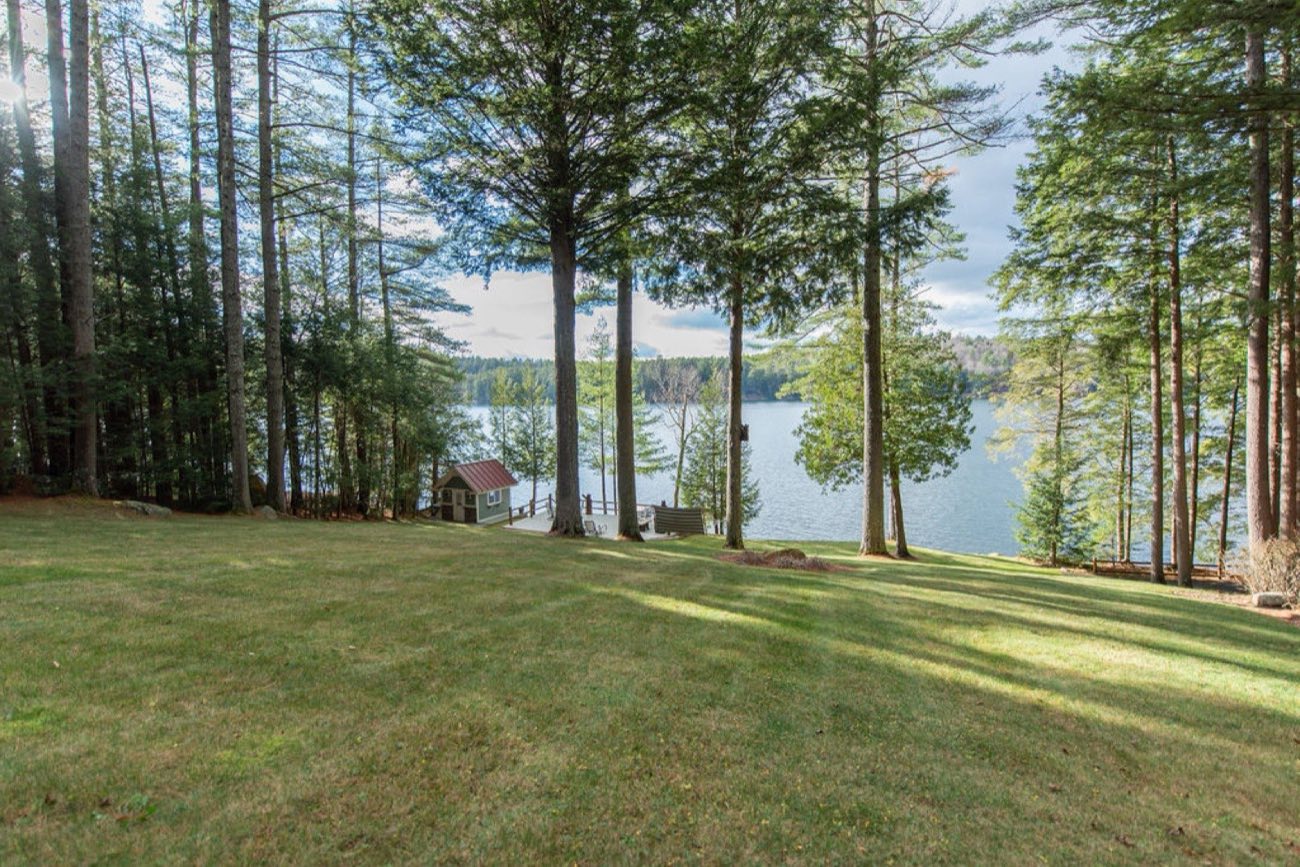 The wide lawn at Camp Sunnyside runs down through tall pines to the dock and the clear blue water of Friends Lake.